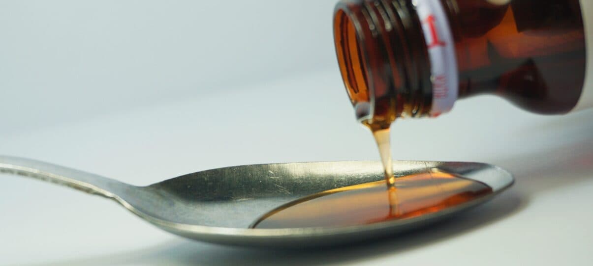 Amber sugar syrup pouring onto a spoon before activated carbon decolorization