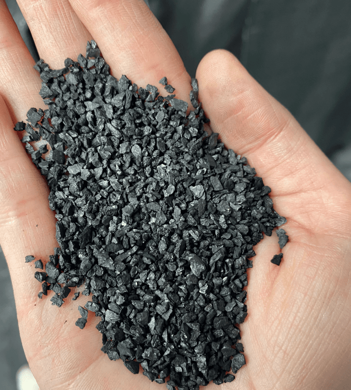 Granular activated carbon particles in hand showing typical 8x30 mesh size for water treatment filter sizing