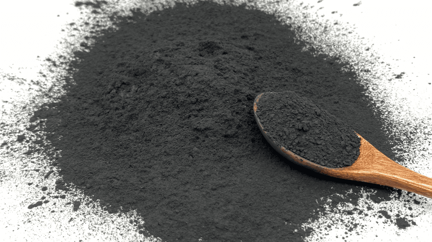 Powdered activated carbon (PAC) with wooden spoon showing fine particle size for water treatment dosing