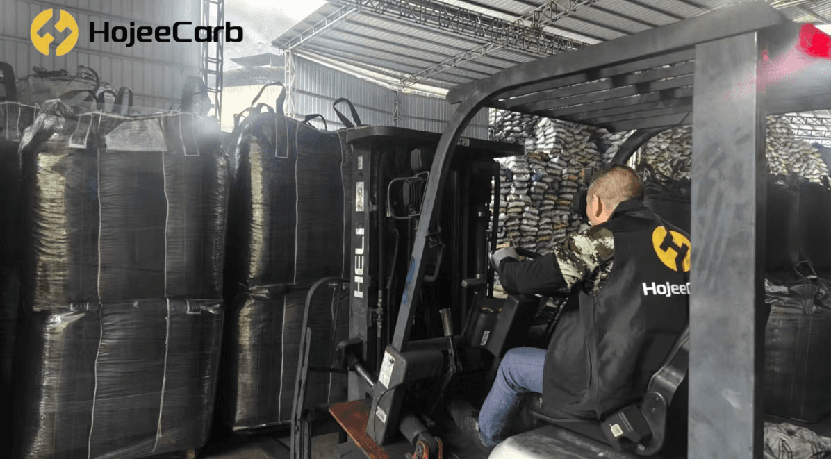 HojeeCarb factory worker in branded workwear lifting a jumbo bag of HojeeGold CG35 gold recovery carbon