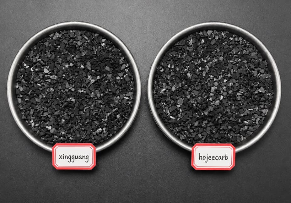 Two coconut shell activated carbon samples placed side by side in metal dishes for visual comparison — our HojeeCarb production carbon next to the buyer's competing brand sample