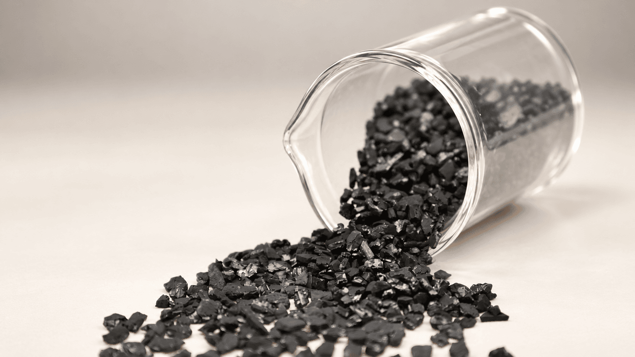 HojeeGold CG33 coconut shell activated carbon granules in lab beaker — 6×12 mesh, iodine ≥1100 mg/g, quality tested before bulk shipment to Sudan CIP gold mine