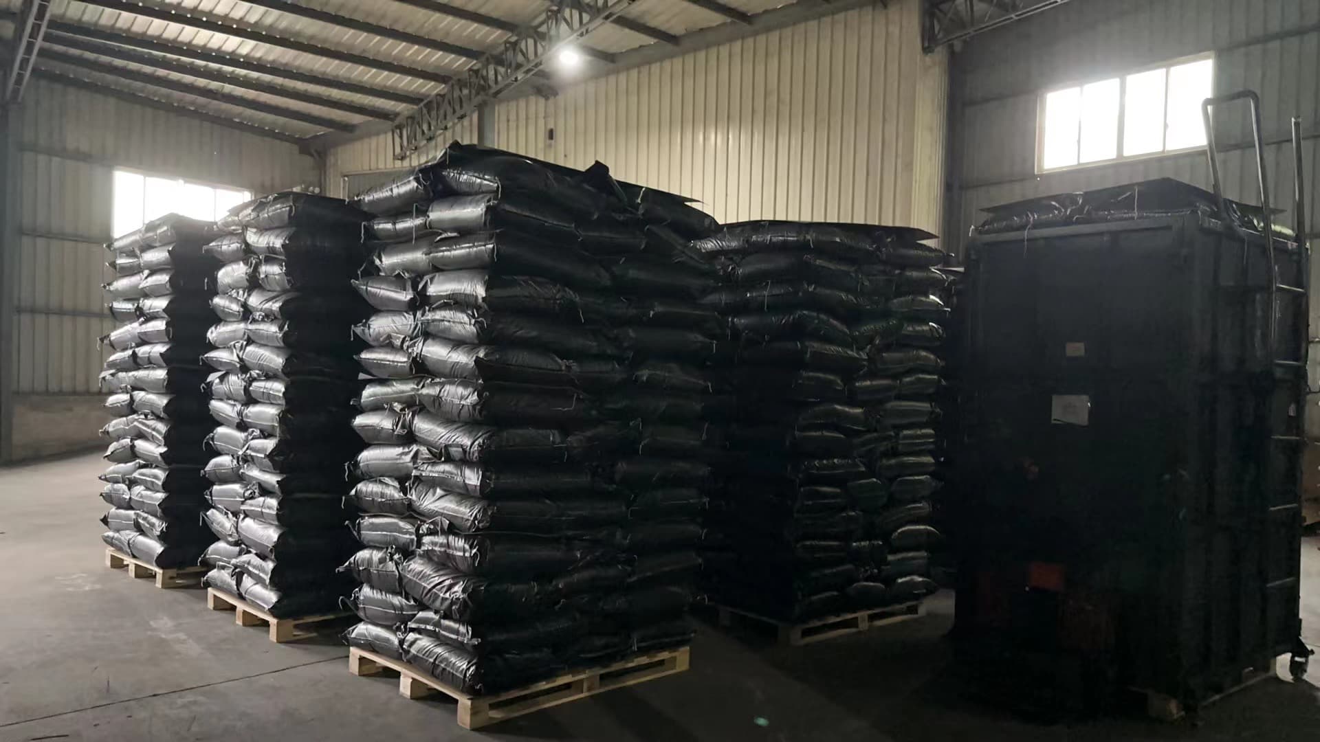 Bulk activated carbon in warehouse — stacked 25 kg bags on pallets ready for shipment