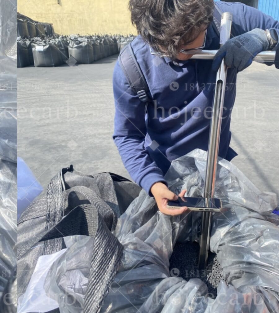 Quality control inspector using a stainless steel sampling probe to collect CuO/MgO activated carbon samples from a bulk ton bag